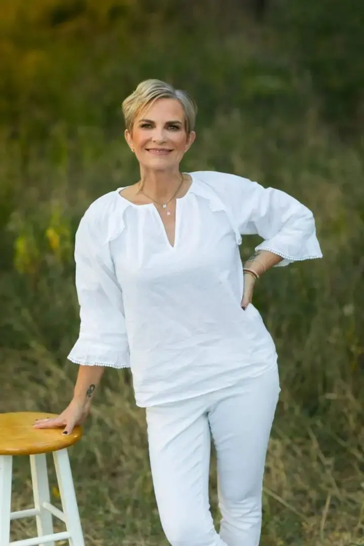 A woman in white is holding her hand on the ground