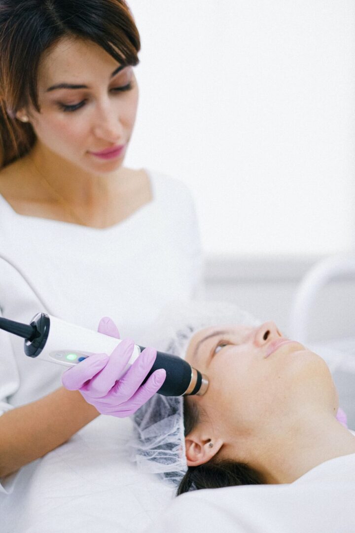 A woman is using an electric device to treat her face.